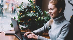 Woman typing on computer in front of a Christmas tree