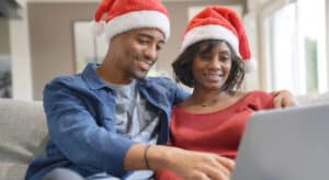 Couple wearing Santa hats looking at a computer